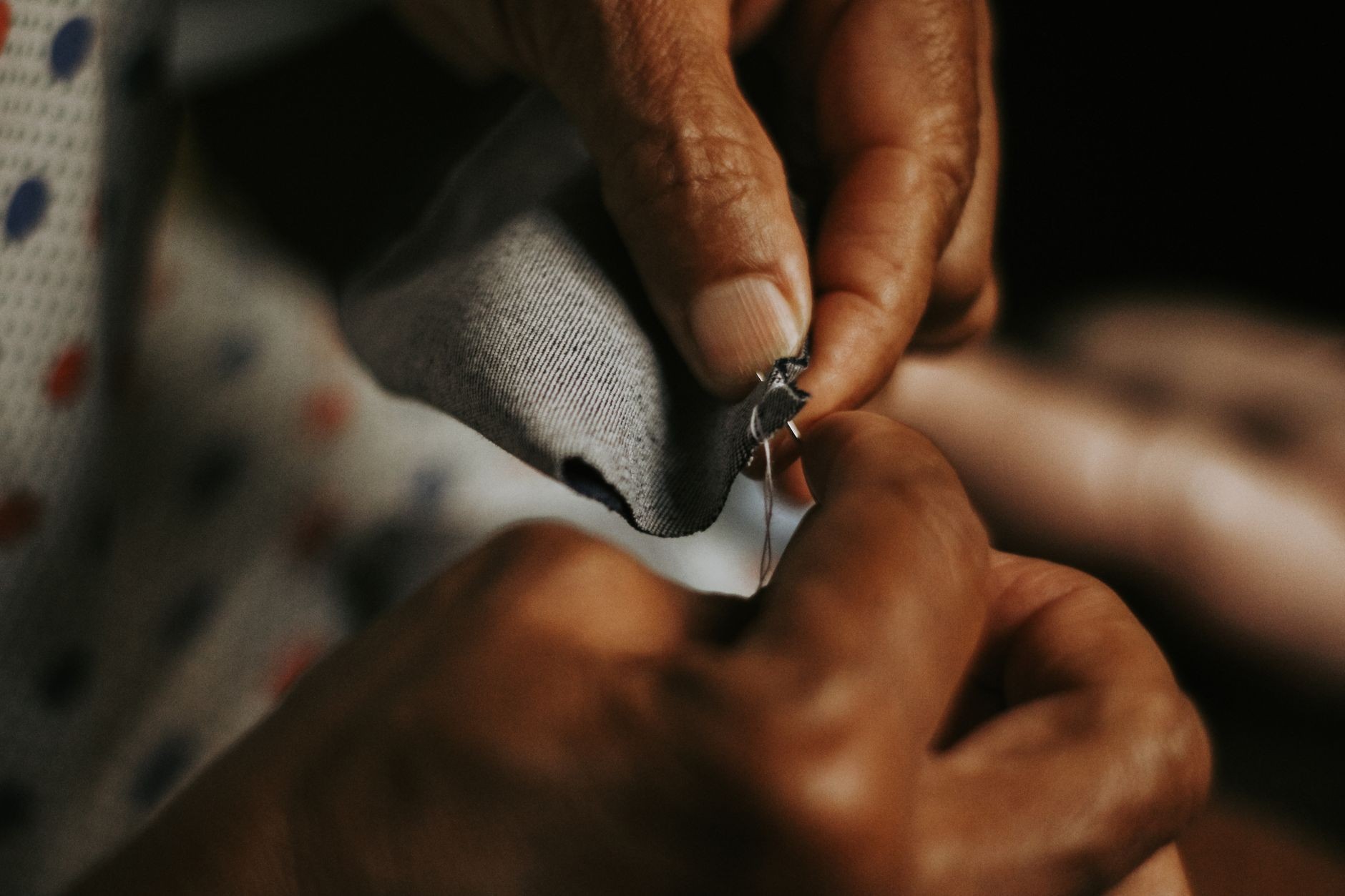 Mains recousant une pièce de tissu avec une aiguille et du fil